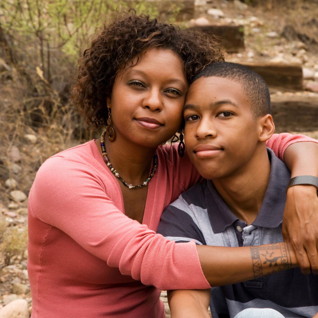 Loving African American mother hugging her handsome teenage son