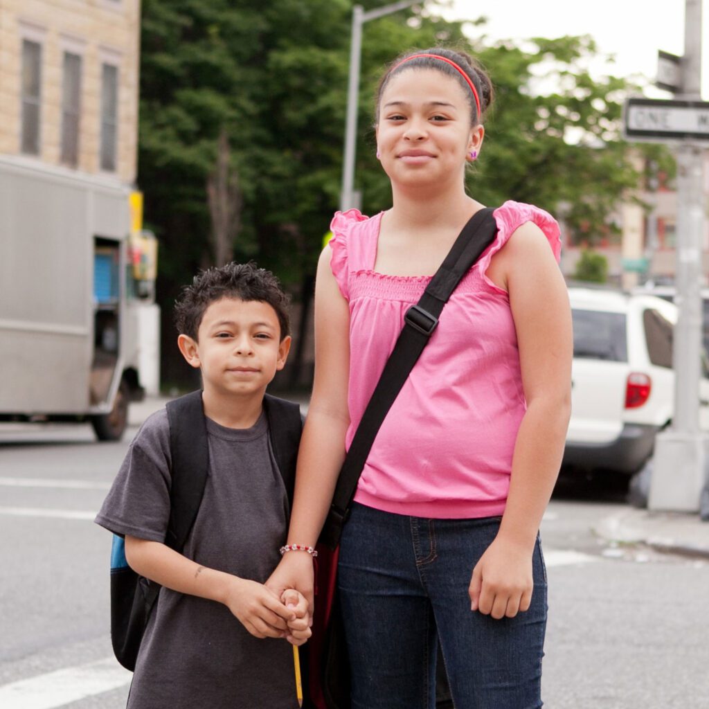Young hispanic sister and brother holding hands on the way to school
